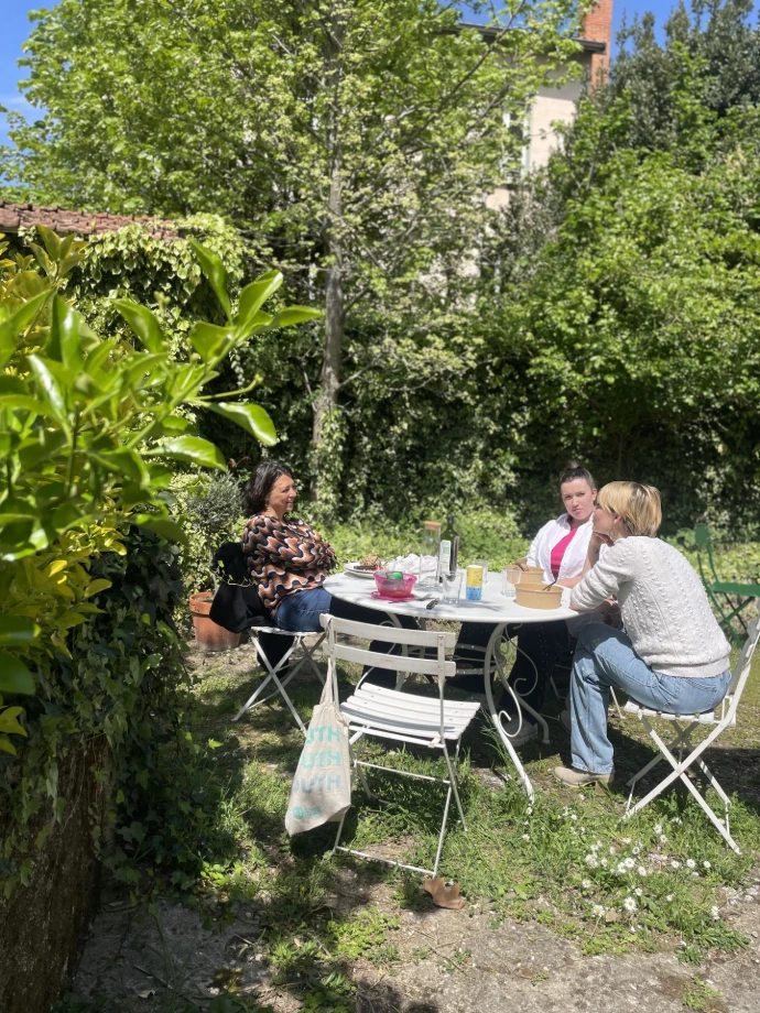 Jardin du MIX Café, tables et chaises de jardin avec coworkers prenant le déjeuner, Titre bureaux privésbeaucoup de plantes vertes et de fleurs au sol.